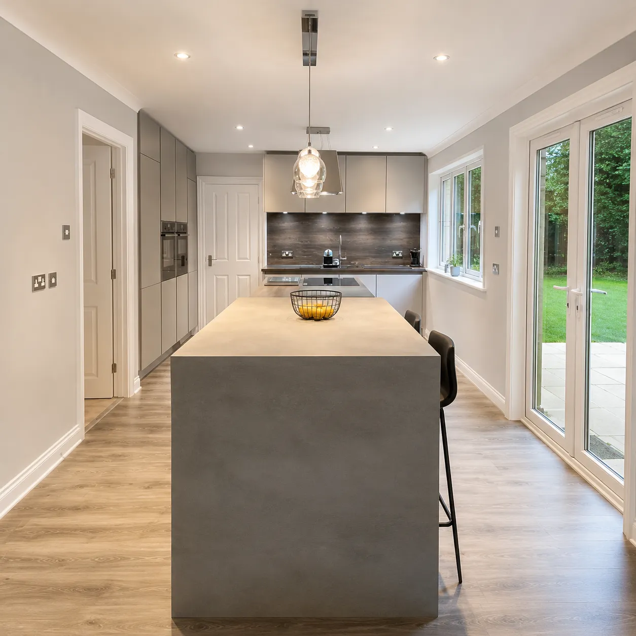 Grey handleless German kitchen with a concrete waterfall island and garden doors